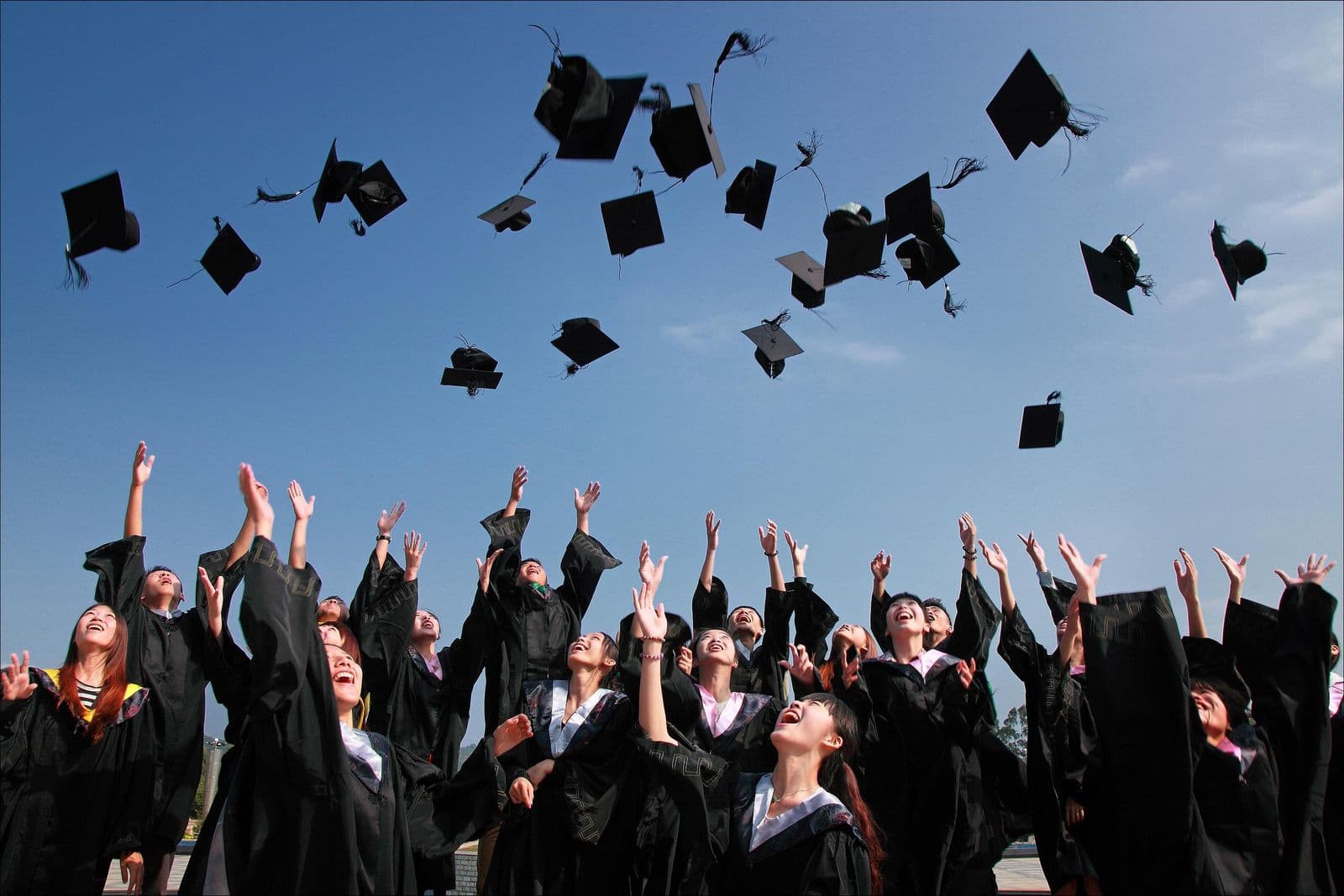 Graduates throwing mortarboards into the air